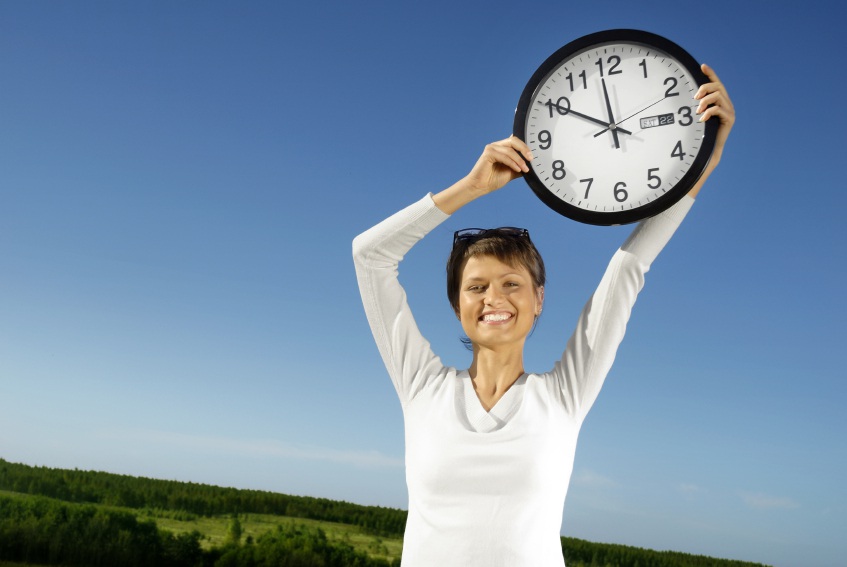 A happy-looking woman holds a clock that reads 11:50